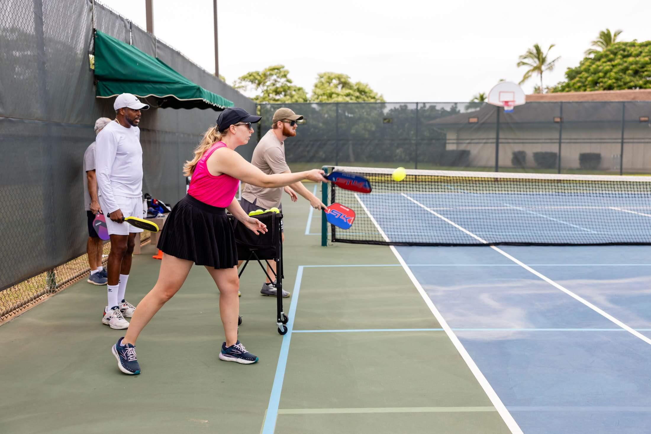 Four people playing pickleball on an outdoor court.