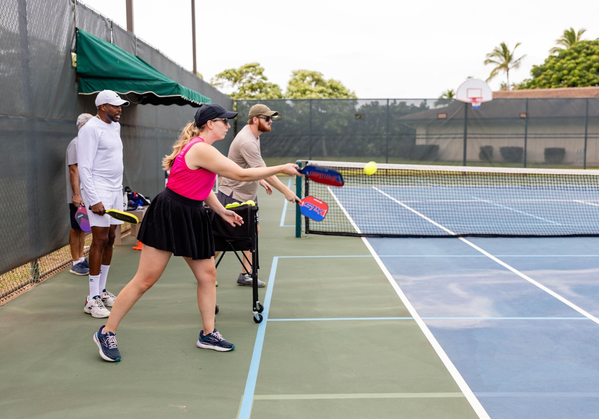 Four people playing pickleball on an outdoor court.
